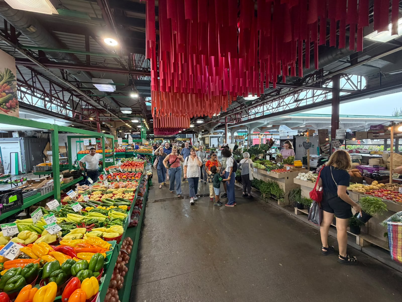 Corredor do Marché Jean-Talon, em Montreal, com bancas de hortaliças e visitante